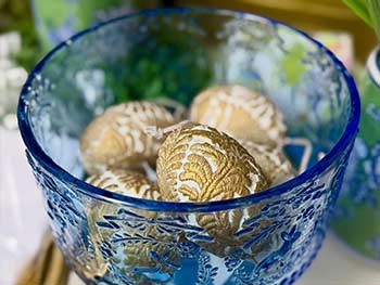 Decorative blue glass bowl filled with gold decorative items on a blurred background
