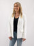 woman in white blazer with black tee and denim